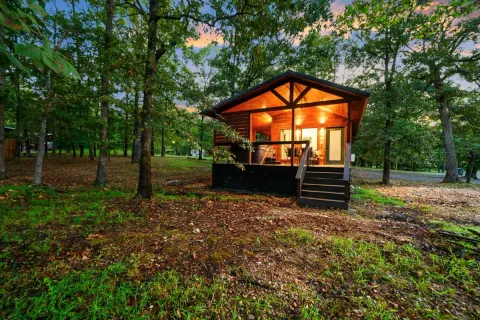 Tree-Mendous, an example HochaCabins rental, with a lit covered porch in the woods