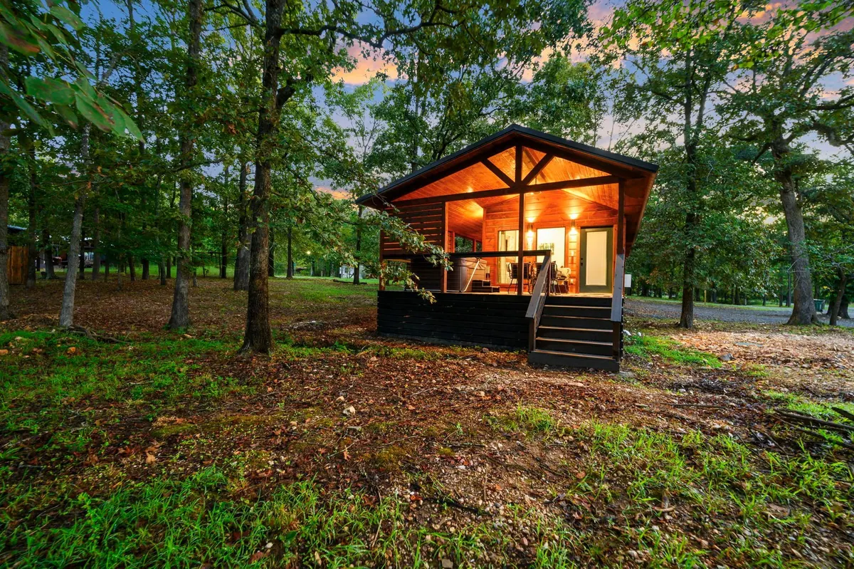 Tree-Mendous, an example HochaCabins rental, with a lit covered porch in the woods