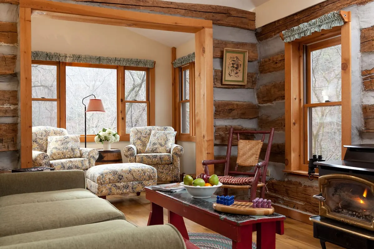 Living room in Redbud Cabin at the Inn & Spa at Cedar Falls, with log walls, large windows and a fireplace